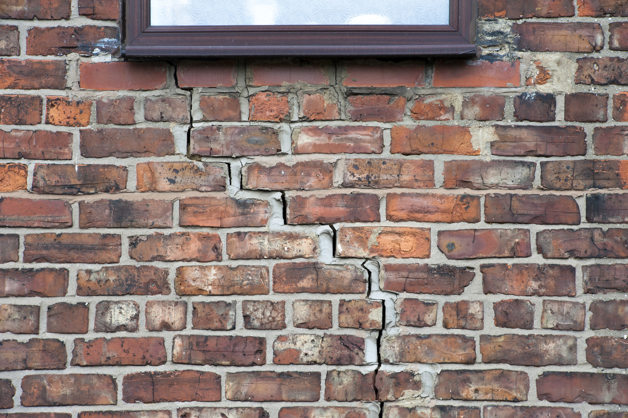 Step cracking damage to brickwork in a wall beneath a window as a result of subsidence.